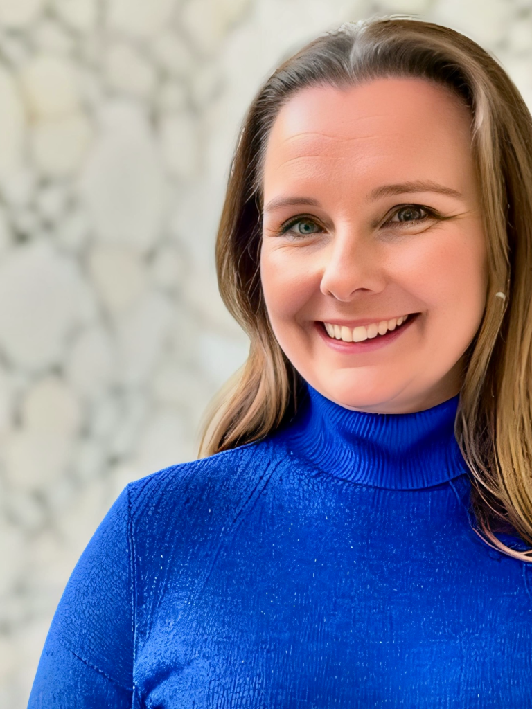 Headshot of Claire bond with light brown hair wearing a vibrant blue turtle neck jumper
