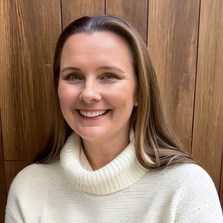 Headshot of Clair Bond with brown hair wearing a cosy white turtle neck jumper.